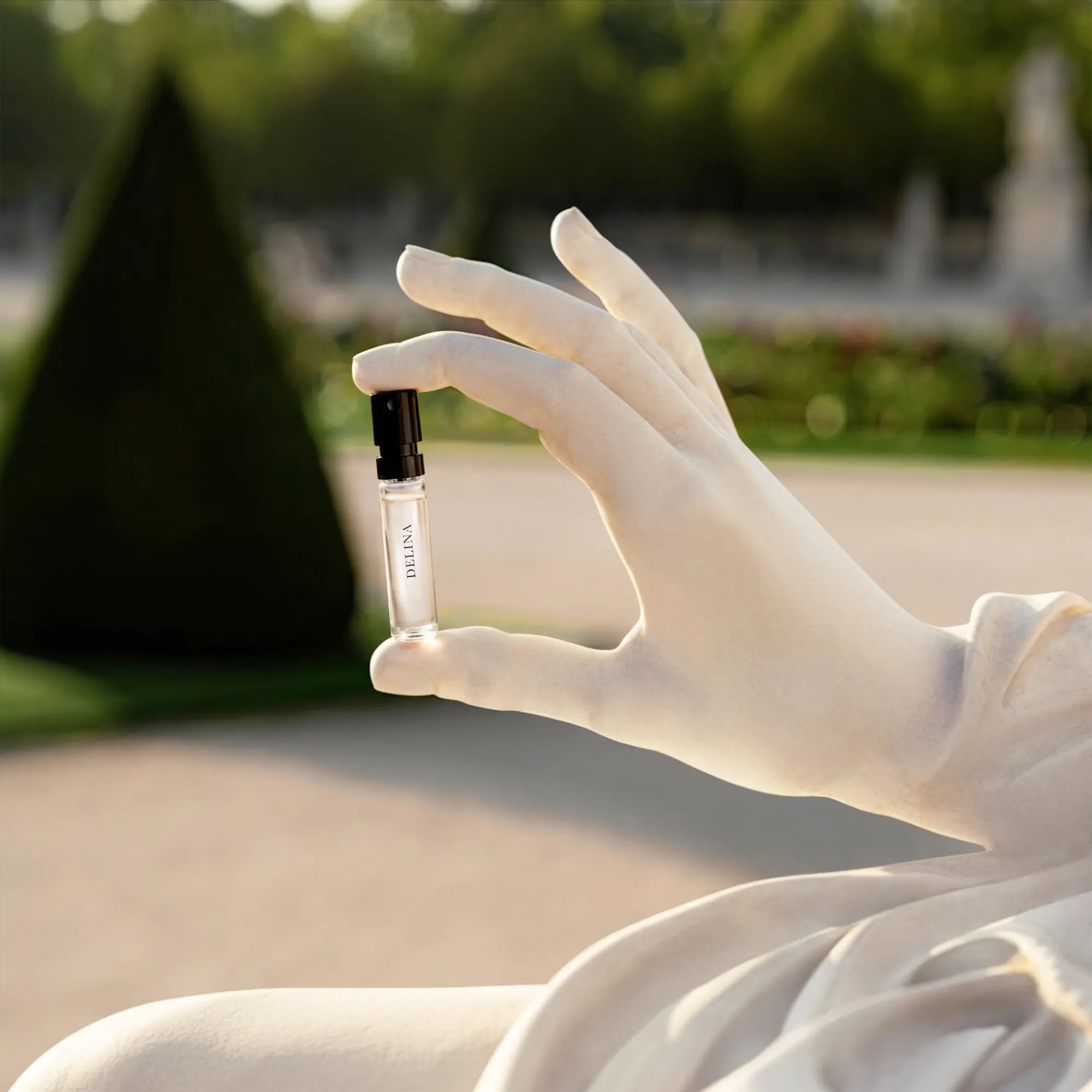 Gloved hand holding a miniature Parfums de Marly perfume vial with a topiary garden blurred behind — ai video production Thinkdiff, photography & art direction by Alex, produced by Thinkdiff AI Production House