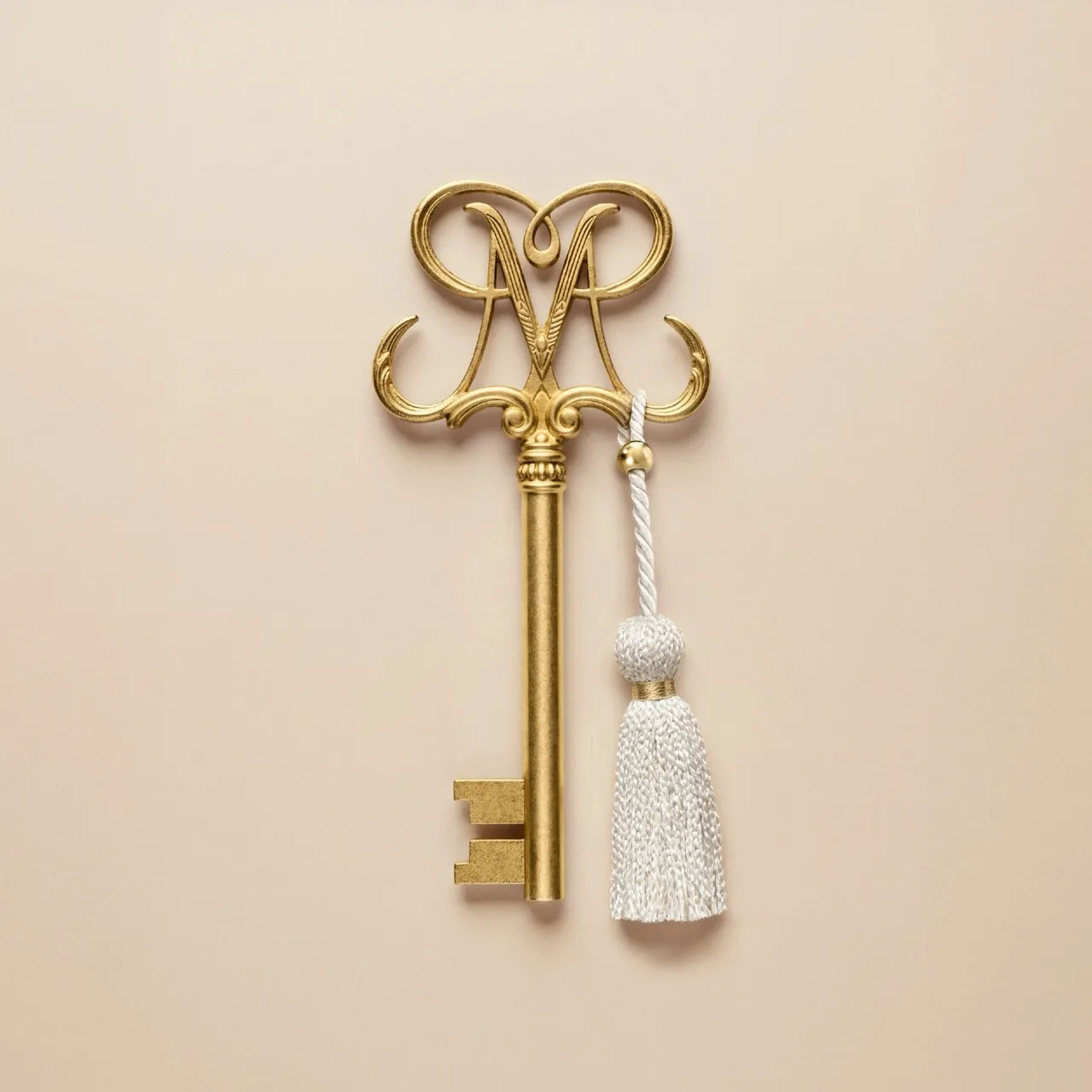 Ornate gold key with a white tassel resting on a soft beige backdrop for the Marly Jardins case study — ai advertising agency Thinkdiff, photography & art direction by Alex, produced by Thinkdiff AI Production House