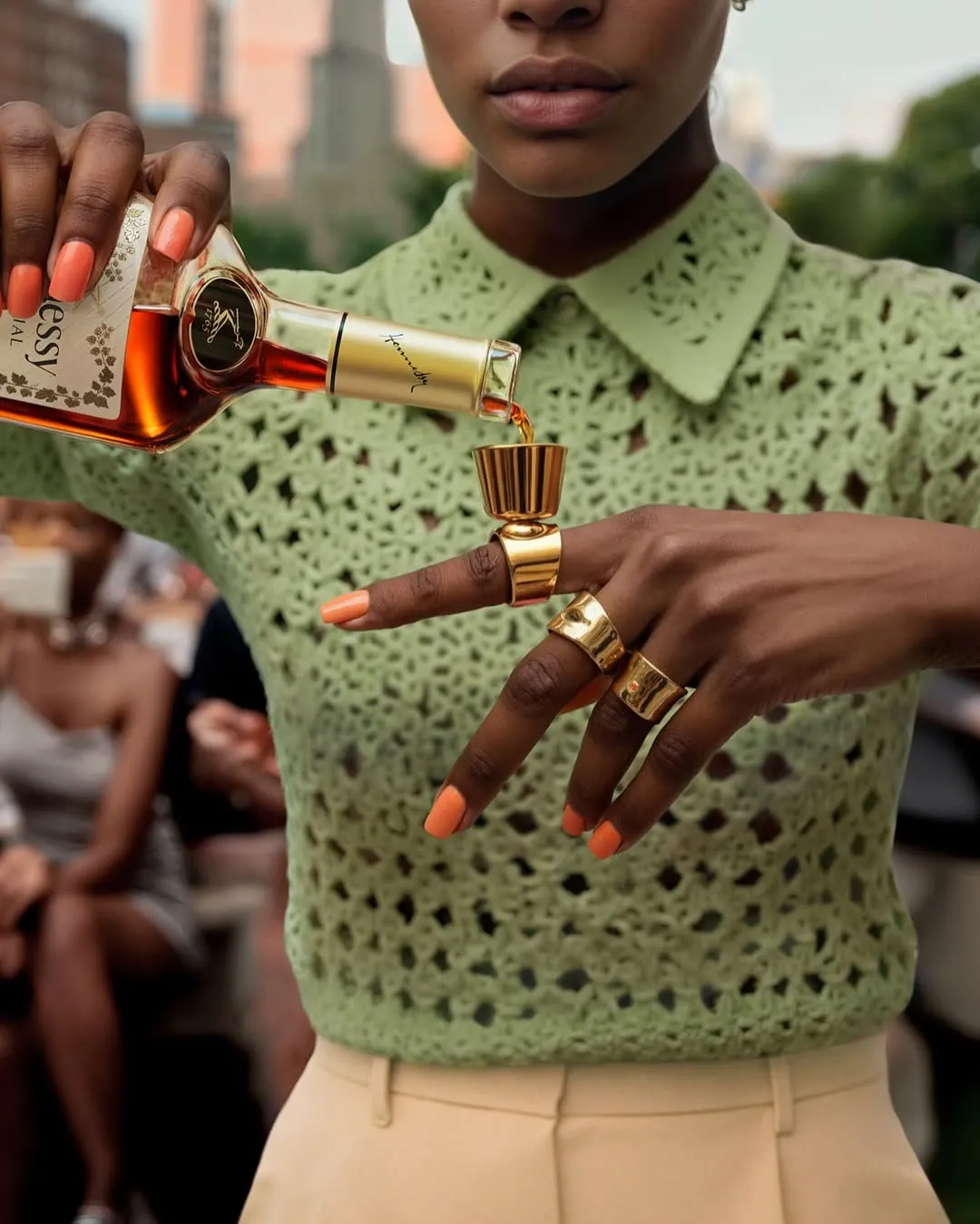 Close-up of a hand with rings pouring a Hennessy bottle, woman in a green crochet top — cgi advertising Thinkdiff, photography & art direction by Thinkdiff AI Production House