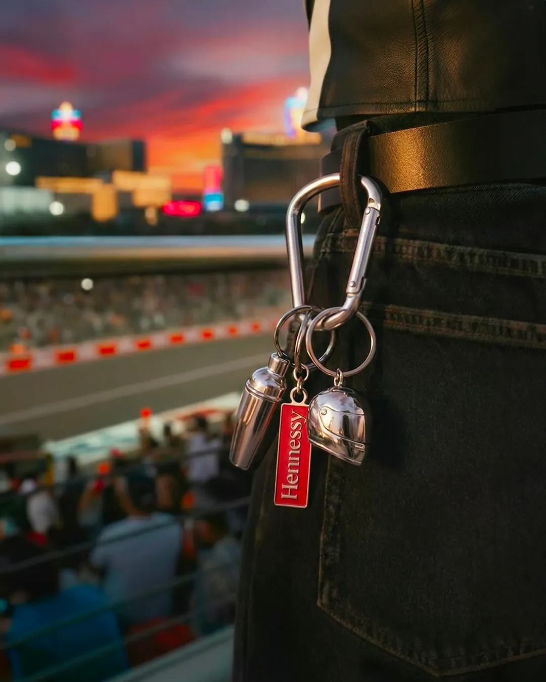 Hennessy keychain and keys hanging from a denim jacket pocket with a racetrack sunset behind — 3d product animation Thinkdiff, photography & art direction by Thinkdiff AI Production House