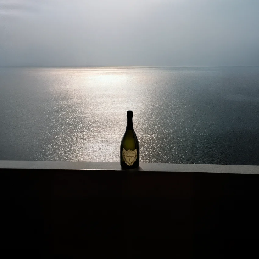 Dom Pérignon bottle silhouetted against a calm sea horizon with sunlight glinting on the water — virtual production studio Thinkdiff, photography & art direction by Pierrick Jégou, produced by Thinkdiff AI Production House