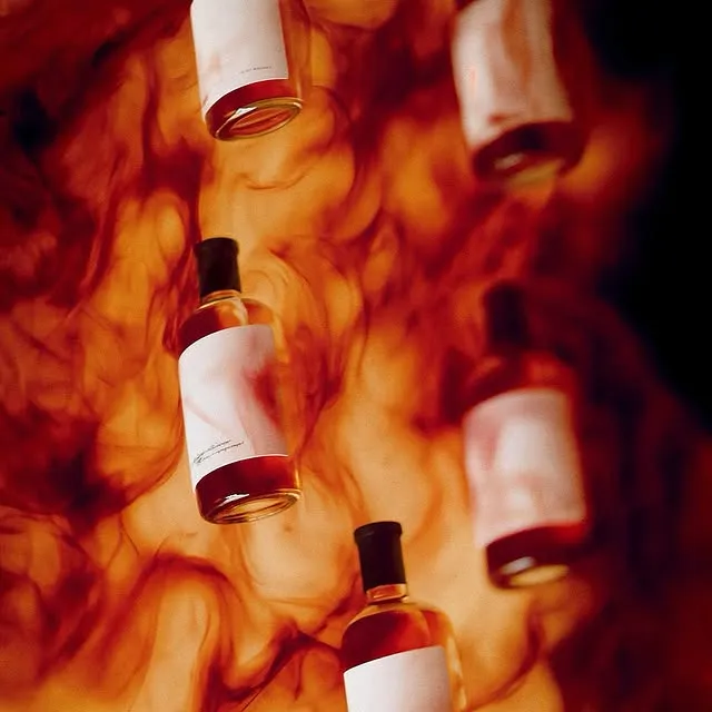 Row of perfume bottles suspended amid swirling amber smoke against a dark background — 3d product animation Thinkdiff, generative AI artwork & art direction by Charlie Faye Mather