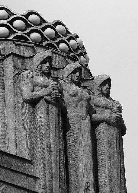 Close-up of Art Deco stone figures with an ornate scalloped crown motif above, carved in classical relief style — virtual production studio Thinkdiff, cover visual for Thinkdiff's copyright law report